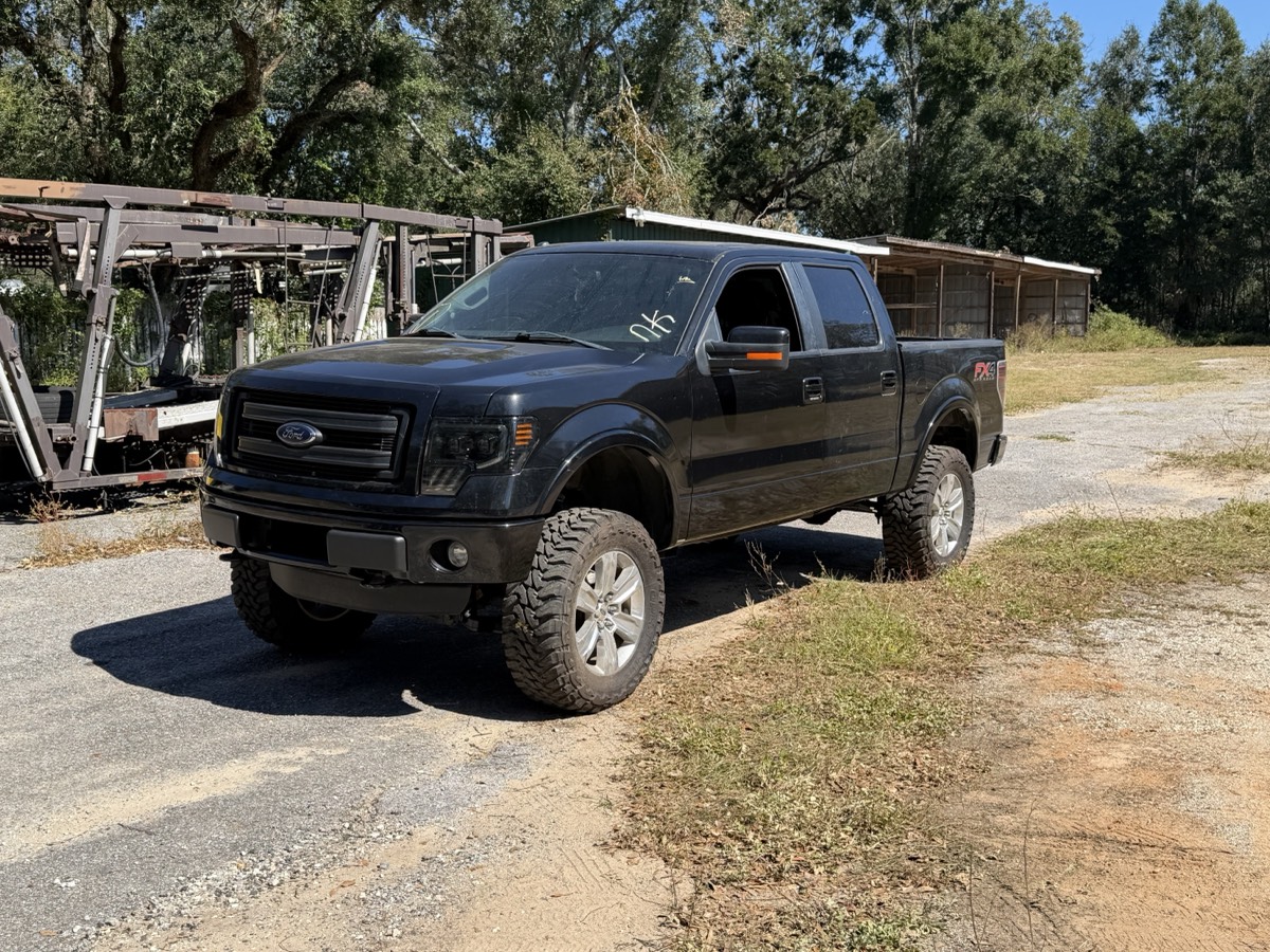 Black lifted Ford F-150 on gravel after a front-end rebuild