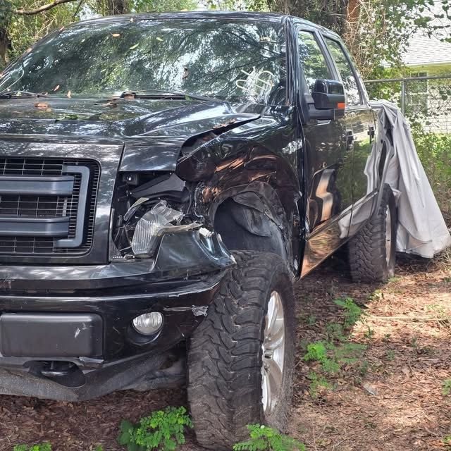 Black Ford F-150 with a crushed front fender, bumper and headlight, before repair