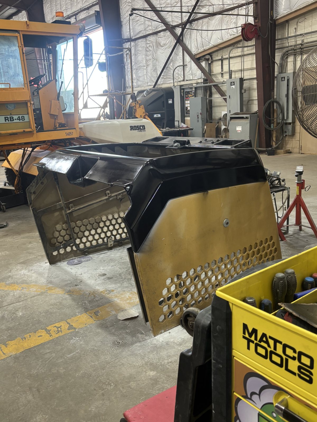 Equipment hood panel hanging for paint beside a tool cart