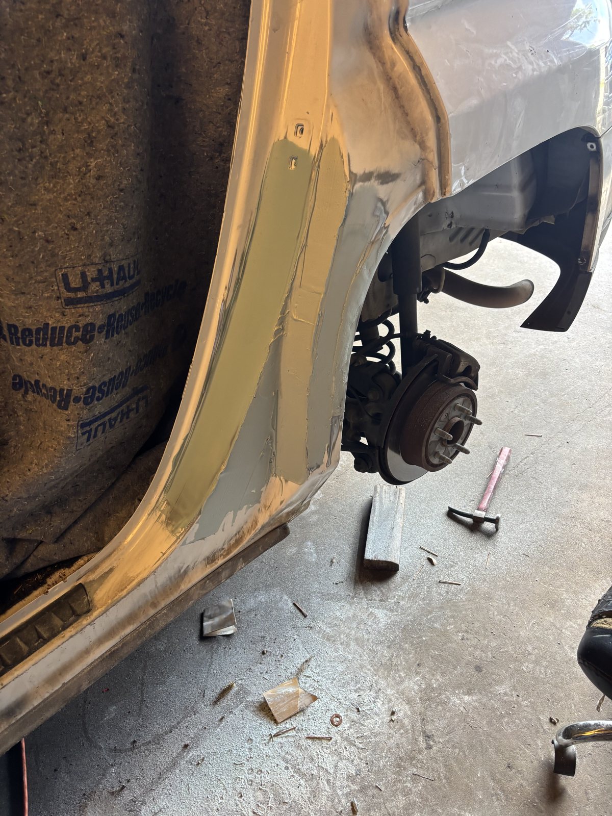 A pickup with the fender off, hub and suspension exposed during panel work